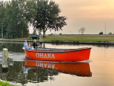 oranje sloep op kanaal met twee personen