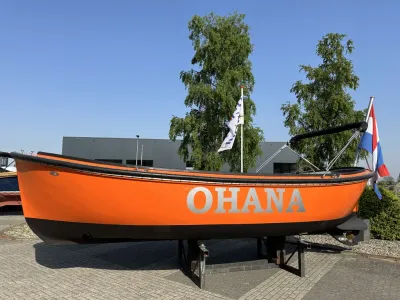 Oranje sloep op bokken bij bedrijfsgebouw