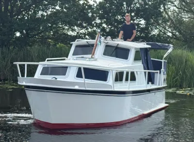 motorkruiser op rustig water bij riet