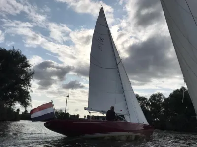 zeilboot op binnenwater met Nederlandse vlag