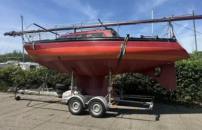 rood zeiljacht op trailer bij jachthaven