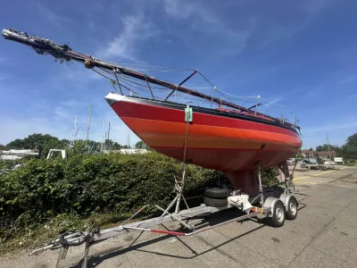 rood zeiljacht op trailer op werf