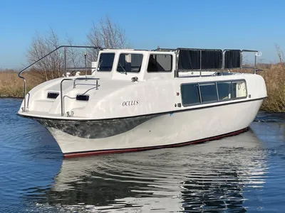 witte motorboot op water bij oever