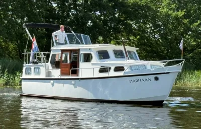 wit motorjacht op rivier bij groene oever