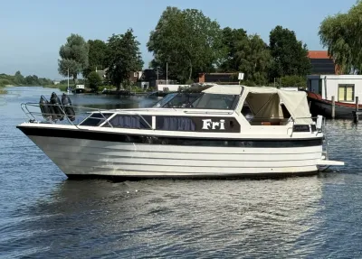 wit motorjacht op rustig water bij oever