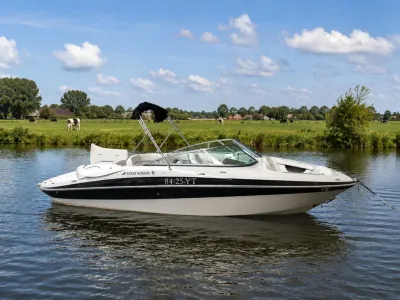 wit-zwarte speedboot op rustig water met weiland