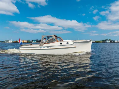 witte cabinsloep op water met blauwe lucht