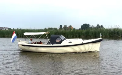 witte sloep op rivier met rietkraag