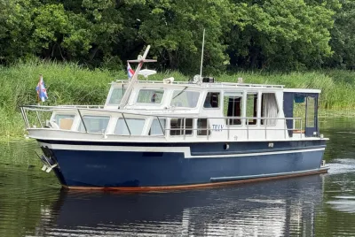 motorjacht op rustig water met groene oever