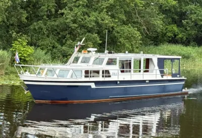 Salonboot op rustig water bij groene oever