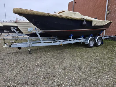 Boot op trailer bij gebouw op onverharde ondergrond