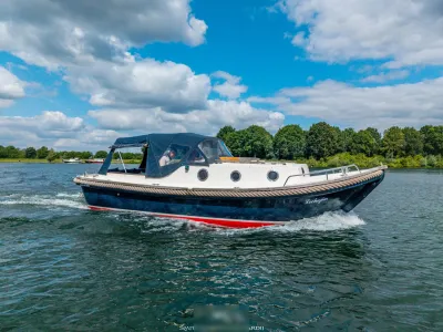cabinsloep op het water met bomen aan de oever
