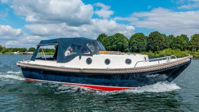 cabinsloep op het water met bomen aan de oever