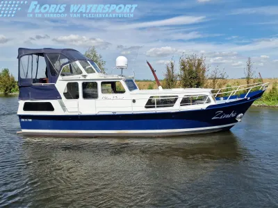 witte en blauwe motorboot op water bij oever