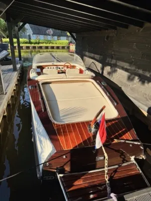 houten klassieke sloep afgemeerd in loods