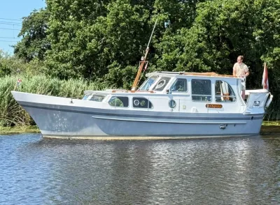 motorjacht op water langs groene oever