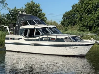 motorjacht op stil water langs groene oever