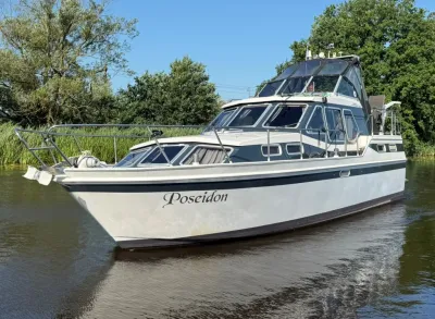 motorjacht op rustig water met bomen op achtergrond