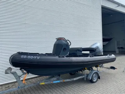 zwarte ribboot op trailer bij loods