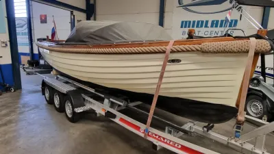witte sloep op trailer in hal
