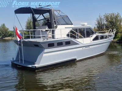 wit motorjacht op water bij de oever