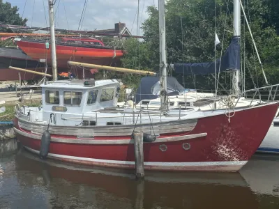 rood motorzeilschip afgemeerd in haven