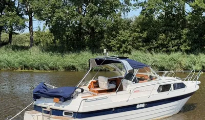 wit motorjacht op binnenwater bij bomen