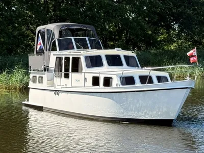 Witte motorkruiser op water bij groene oever