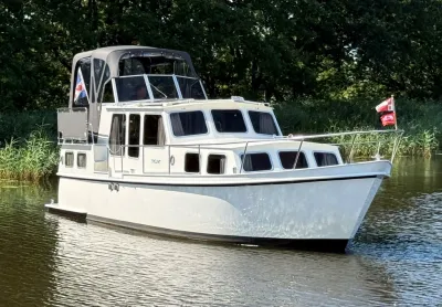 Witte motorkruiser op water bij groene oever