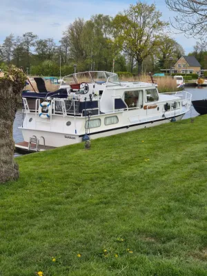 witte motorboot aangemeerd langs oever