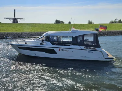 motorjacht langs dijk met molen