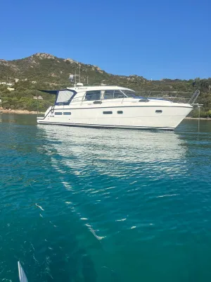 witte motorboot voor de kust met heuvels
