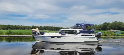 wit motorjacht op kanaal bij riet