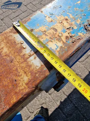 Roestig metalen bokkenwagendeel met meetlint