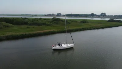 zeiljacht op rivier bij rietvelden