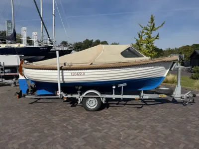 creme witte sloep op trailer