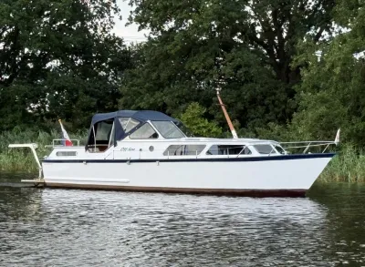 witte motorkruiser langs de oever