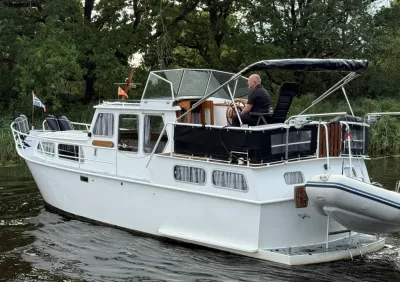witte motorboot op rustig water met persoon aan roer
