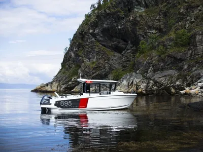 Motorboot in kalm water bij rotsachtige kust