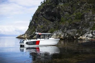 Motorboot in kalm water bij rotsachtige kust