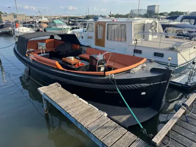 zwarte sloep met oranje kussens in jachthaven