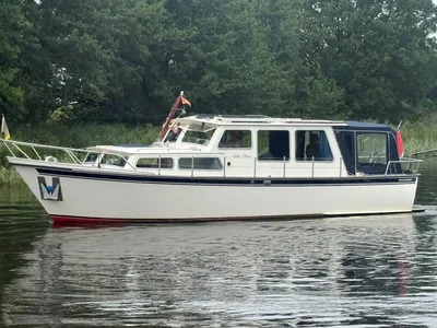 wit motorjacht op stil water bij bomen