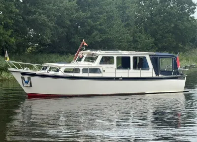wit motorjacht op stil water bij bomen