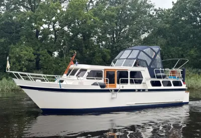 wit motorjacht op rivier met bomen