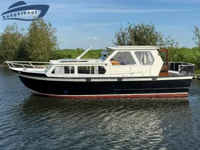 wit-zwart motorjacht bij groene oever