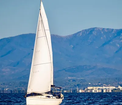 zeiljacht op open zee met bergen op de achtergrond