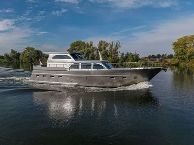 zilverkleurig motorjacht op rivier bij bomen