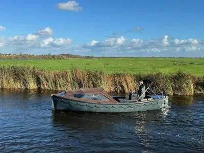 sloep op water bij riet en grasland