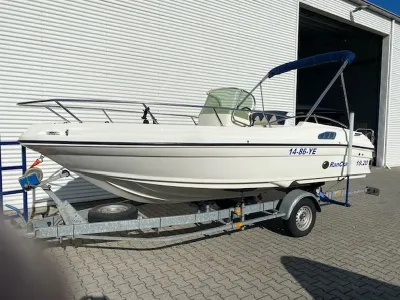 witte consoleboot op trailer bij loods