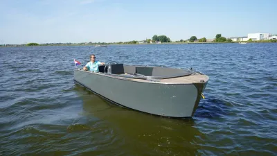grijze sloep met teakhouten dek op open water